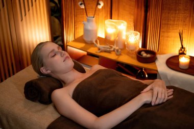 Beyaz kadın müşteri stres önleyici spa masajının keyfini çıkarıyor ve lüks otel ya da otelde sıcak mum ışığında güzellik teniyle eğleniyor. Sessiz.