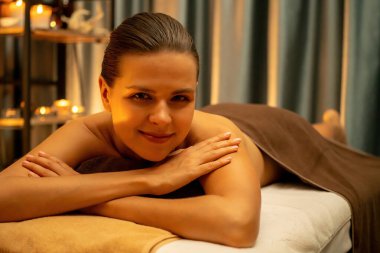 Beyaz kadın müşteri stres önleyici spa masajının keyfini çıkarıyor ve lüks otel ya da otelde sıcak mum ışığında güzellik teniyle eğleniyor. Sessiz.