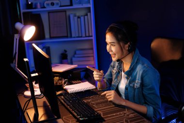 Sunucu kanalı Asyalı etkileyicisi canlı yayında konuşuyor. Sosyal medyada kulaklık takıyor, bilgisayar kaydı yapıyor, dinleyicileri selamlıyor ve Neon Modern Stüdyoları 'nda online olarak koçluk yapıyor. Taktik.