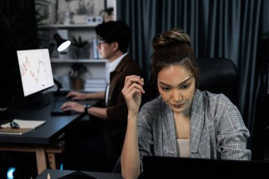 Modern ofiste gece geç saatlerde arka tarafta çalışan iş arkadaşı ile birlikte veri analizi sosyal medya çevrimiçi proje işini rapor etmek için bilgisayara odaklanan iş kadınının ciddi yüzü. İnfobahn.