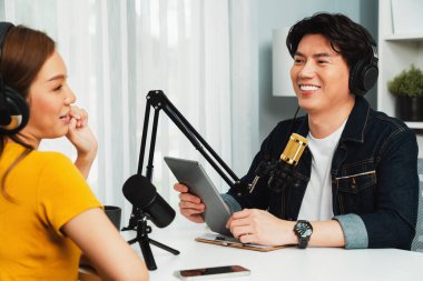 Gülümseyen radyo etkili sunucu elinde tablet, kulaklık takıyor kadın konuşmacı sosyal medya online canlı yayın kanalı ile röportaj yapıyor ve sabah stüdyo kaydında paylaşım linkini paylaşıyor. İnfobahn.