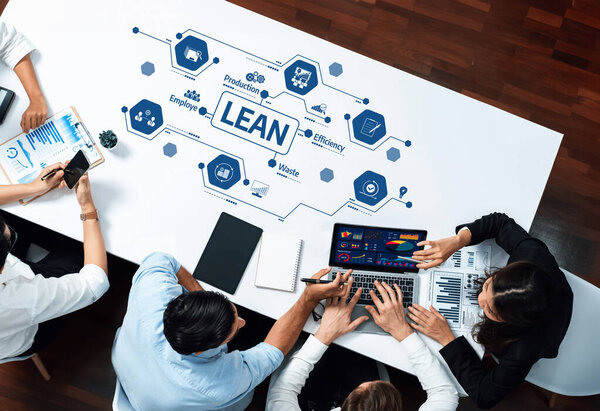 A diverse team collaborates in a modern office, analyzing lean management strategies. They utilize technology and data for improved efficiency and productivity in their projects. Amity
