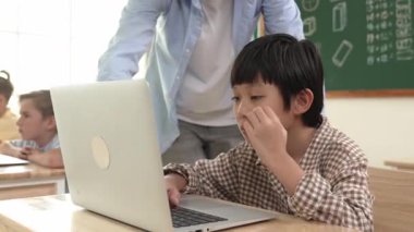 Kafkasyalı öğretmen Asyalı öğrenci kodlama mühendisliğine yardım ederken çeşitli öğrenciler yapay zeka yazılımı kullanıyor. Zeki, mutlu, çekici çocuklar, oturma ve programlama sistemi. Eğitim. Pedagoji.