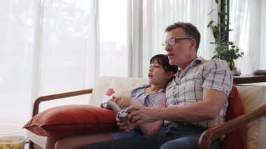Granddaughter teaching grandfather play console game, entertainment hobby. Old senior use technology communicate with new generation kid cross generation gap strengthen family bond. Divergence.