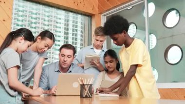 Akıllı robotlar sınıfta dizüstü bilgisayar ekranını işaret ederken, beyaz bir öğretmen yorum yapıyor ya da öğrencilere tavsiye veriyor. Öğretmen bilgisayar kullanırken çeşitli öğrencilerin ders verirken not alması. Öğretim