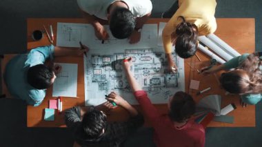 İnşaat mühendisi ekibinin renkli paletlerle toplantı masasında yazı yazması. Yönetici proje planlarına bakarken bir grup farklı insan plan yapıyor ve not alıyor. Sempozyum.