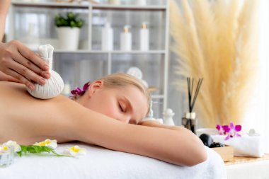 Sıcak bitkisel top spa masaj vücut tedavisi, masör kadın vücuduna nazikçe şifalı bitki torbası bastırıyor. Aromaterapi dinlenme sükuneti ve sükuneti kaplıca salonundaki atmosferi aydınlatıyor. Sessiz.