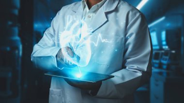 Doktorun tableti tutmasına ve laboratuvarda bulanık bir geçmişi olan kalp hologramıyla kalemi işaret etmesine yakın durun. Sağlık çalışanı semptomları kontrol edip kalp ameliyatına hazırlanıyor. Teknoloji. İyileştirici.