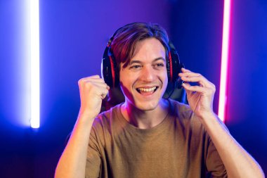 Kazanmak için çevrimiçi oyun oynayan akıllı flama makinesinin sunucu kanalı, neon ışıklı odada seçilen takım yarışması için izleyicilerle birlikte canlı yayında canlı yayında kulaklık takıyor. Bireysel.