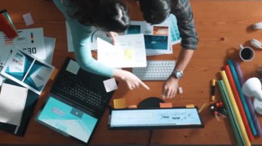 Tasarımcı yazma fikri ekrana bakarken proje yöneticisinin üst görünümü. Akıllı iş adamlarını kapat ve tasarımcı palete bakarken logo tasarımı fikrini açıkla. Sempozyum.