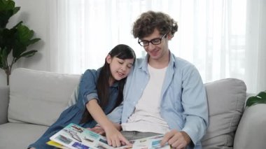 Komik liseli kız masal kitabına işaret ederken mutlu bir baba hikâyesi ve dokunaklı bir jest. Öğrenciler ebeveyn ararken peri kuyruğu hakkında konuşmaktan zevk alırlar. Aile eğlence konsepti. Pedagoji.