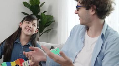 Mutlu bir babanın, ukulele çalan ve şarkı söyleyen akıllı kızına bakışının arkası. Mutlu baba motive oldu ve Amerikalı liseli kızı gitar çalmaktan zevk almaya teşvik etti. Aile eğlencesi. Pedagoji.