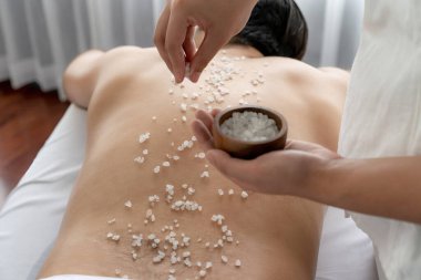 Lüks spa salonunda sıcak mum ışığı atmosferi olan lüks kaplıcalarda deri dökme tedavisi gören mutlu bir adam. Sağlık kaplıcasında güzellik tedavisiyle tuz temizliği. Sessiz.