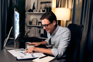 Akıllı iş adamı iş paragrafı dinamik pazarlama analizi planını analiz ediyor. Kağıt kağıtları ve bilgisayar monitörü raporlarını gece evdeki belge verileriyle karşılaştırmak için hazırlıyor. Bireysel.