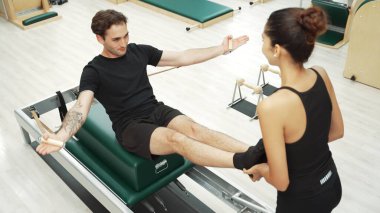 Beden eğitiminde birlikte pilates egzersizi yapan birkaç mutlu antrenör. Çekirdek gücü ve dengeyi arttırmak için reformcuda yüz poz veren İspanyol bir adam. Alışkanlık.