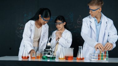 Zeki kız deney yapmak için heyecanlanan çeşitli öğrenciler iken beher kabına renkli solüsyon döker. Profesyonel bilim adamı kimyasal teoriyle kara tahtada deney yapmaya hazırlanıyor. Öğretim.