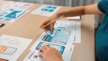 Mobil uygulama için kullanıcı arayüzü prototipi ya da masadaki program modeliyle birlikte web sitesi planlaması yapan bir şirket çalışanı. UX UI tasarımcısı kullanıcı dostu arayüz planını dikkate alır. Sinerjik