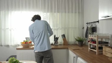 Mutlu baba yemek pişirirken müziğe geçiyor ve modern mutfakta öğle yemeği hazırlıyor. Aktif baba, sebze ve mutfak gereçleri ile çevrili sağlıklı yemek ya da salata yaparken şarkıyla dans ediyor. Pedagoji.