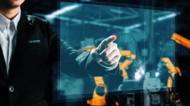 Engineer use cybernated robotic software to control industry robot arm in factory . Automation manufacturing process controlled by specialist using IOT software connected to internet network .