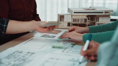 Mimari tasarım oturumunda yer alan çeşitli profesyonellerden oluşan bir grup, modern bir çalışma alanı ortamında planlar, çizimler ve modeller üzerinde işbirliği yaparak yaratıcılık ve takım çalışması sergilediler. SACTR