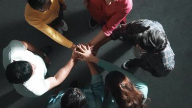 Zeki iş adamlarının birlikte çalışıp el ele tutuşması. Bir grup yetenekli iş adamının beyin fırtınası yapıp toplantı odasında el ele tutuşmalarının havadan görüntüsü. Sempozyum.