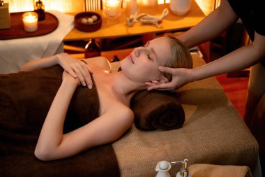 Beyaz kadın stres önleyici kafa masajı yapmaktan ve lüks otel veya otelde sıcak mum ışığında yüz güzelliği eğlencesi yapmaktan zevk alıyor. Sessiz.