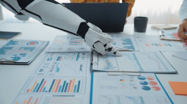 Bir robotik kol, modern bir çalışma alanında teknoloji ve analitik arasındaki sinerjiyi vurgulayan çeşitli iş raporları ve grafikleriyle etkileşime girer. Noogenesis