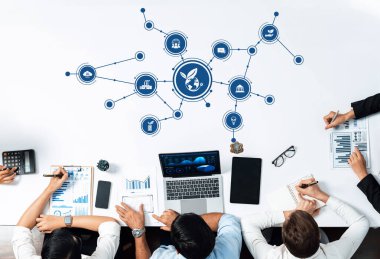 Teknoloji stratejileri üzerinde çalışan ve grafikler ve temiz bir çalışma alanındaki bir dizüstü bilgisayarla gösterilen yeşil kavramlara odaklanan iş adamlarının hava görüşü. Dostluk