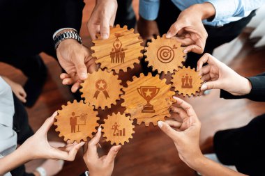 Modern ofis ortamında işbirliğini vurgulayan, başarı ve başarı sembolleriyle ahşap dişlileri tutan takım çalışmasının yaratıcı bir temsili. Dostluk