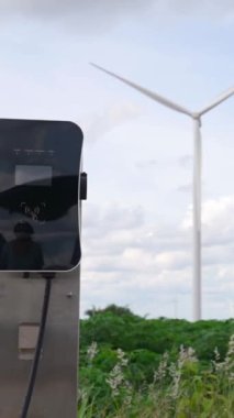 Çevreyi korumak için rüzgar türbininden yeşil ve yenilenebilir enerjiyle çalışan şarj istasyonunda şarj edilen gelişmiş gelecek enerji altyapısı konsepti.