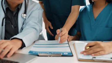 Hastane masasında birlikte çalışan ve tıbbi tedavi planlayan çeşitli profesyonel sağlık görevlileri. Takım çalışması başarılı hastalıklara ve hastalıklara yol açar. Ağır çekim. Katı.