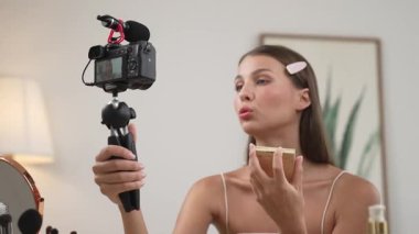 Sosyal medya için güzellik ve kozmetik video içeriği hazırlayan genç bir kadın. Güzellik blogcusu kameraya gülümserken seyircilere ve takipçilere güzellik bakımını gösteriyor. Düzenle