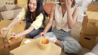 Çekici bir oda arkadaşı oturma odasında paket paketlerken pakette konum yazıyor. Mutlu satıcı birlikte çalışıyor ve teslimat paketini hazırlıyor. Girişimci kargo kutusu paketliyor. Myrmidon.