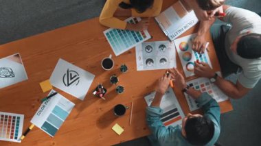 Proje yöneticisi renk paletleri seçerken tasarımcının tablete baktığı yukarıdan aşağıya hava görüntüsü. Profesyonel grafik tasarımının en üst görüntüsü ve logoya bakın. Yetenekli ekip grafikleri seçiyor. Sempozyum.