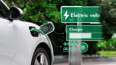 Elektrikli araba, doğal parktaki temiz enerji şarj istasyonundan gelen fütürist akıllı EV şarj cihazının dijital batarya durumu hologramıyla şarj oluyor. Gelecekçi çevre dostu EV araba. İnceleyin