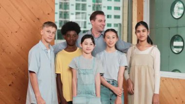 Mutlu öğretmen ve çeşitli öğrenciler kameraya gülümserken ayakta duruyorlar. Profesyonel akıllı eğitmen ve karışık ırk olan lise öğrencileri kameraya neşeli pozlar veriyor. Öğretim