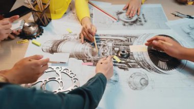 Teknik çizimler ve araçlarla çevrili, takım çalışması ve yaratıcılığı sergileyen bir makine mühendisliği projesi üzerinde işbirliği içinde çalışan çeşitli bireyler. SACTR