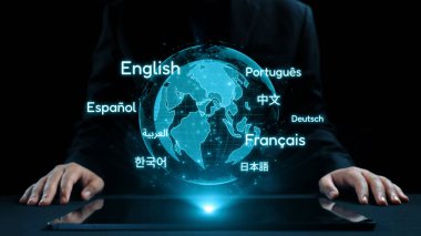 Bir işadamı, dijital dünyada iletişimin ve küresel bağlantının önemini vurgulayarak, çeşitli dilleri gösteren holografik bir küreyle etkileşime giriyor. Dörtgen