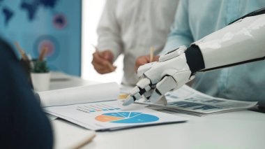 Robotik bir el, günümüz iş ortamında teknoloji ve yeniliklerin kesişiminin gösterildiği modern ofis ortamındaki iş haritalarına işaret eder. Noogenesis