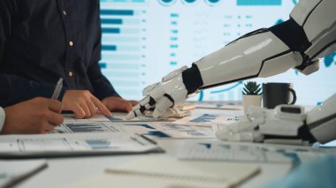 Modern bir ofiste bir insan ve bir robot bir iş görüşmesi sırasında işbirliği yaparlar. Konferansta tablodaki tablo ve belgelerle veri analizi, takım çalışması ve yenilik üzerinde duruluyor. Noogenesis