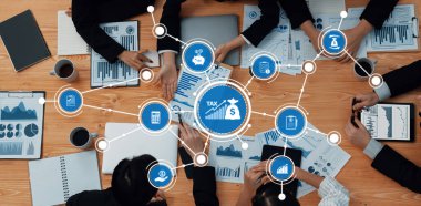 Vergi stratejileri, dijital çizelgeler ve takım işbirliğinin yer aldığı bir iş toplantısının havadan görüşü, mali planlama ve analizi vurguluyor. Dostluk