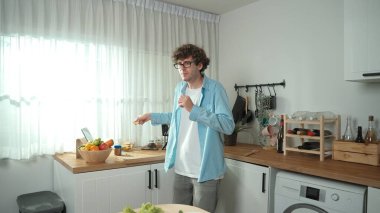 Mutlu baba yemek pişirirken müziğe geçiyor ve modern mutfakta öğle yemeği hazırlıyor. Aktif baba, sebze ve mutfak gereçleri ile çevrili sağlıklı yemek ya da salata yaparken şarkıyla dans ediyor. Pedagoji.