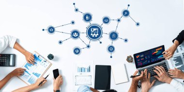 Veri yönetimi ve strateji oturumlarına katılan, dizüstü bilgisayar ve çizelge kullanan, modern bir çalışma alanında işbirliği çabalarını sergileyen dinamik bir ekip. Dostluk