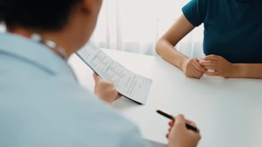 Klinikteki ya da hastane ofisindeki doktor randevusuna katılan hasta, tıbbi tedavi seçeneklerini tartışıyor ve muayene sonuçlarını ya da hastalıkla ilgili tıbbi kayıtları açıklıyor. Ağır çekim. Katı.
