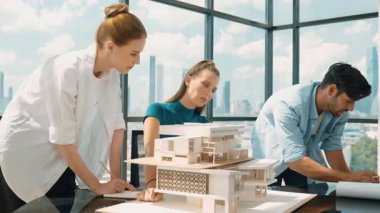 Beyaz proje yöneticisi dizüstü bilgisayar analiz verilerini kullanırken, mimar mühendis ekibi ev modeli inşaatını analiz etmek için birlikte çalışıyor. Bir grup tasarımcı ev tasarımı hakkında konuşuyor. İzleme