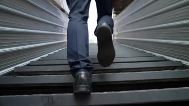 Merdivenlerden çıkan başarılı iş adamının bacağına yakın plan. Müdürün iş yerini değiştirmesi, yeni bir şey keşfetmesi, gelişmesi, terfi etmesi ya da gün ışığına çıkması. Yükseliyor. Bacağa odaklan. Sevinçli..