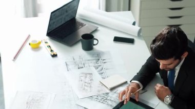 Ofiste dizüstü bilgisayar tasarımı kullanan mimar mühendisi, planlama ve ekipman dağınıklığı ile toplantı masasında otururken. Projede çalışan yetenekli inşaat mühendisi. Hizalama.