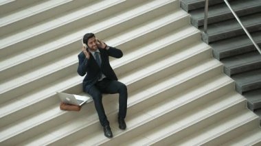 Merdivenlerde otururken kulaklıktan müzik dinleyen zeki bir iş adamı. Mutlu menajer dans ederken ya da müzikle uğraşırken gülümsüyor. Yatırımcı iyi haberler alıyor, terfi alıyor. Sevinçli..