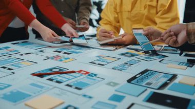 Yenilikçi tasarım kavramları geliştirmek için dijital cihazlar ve renkli kağıtlar kullanan çeşitli bir beyin fırtınası oturumunda yer alan canlı bir sahne. SACTR