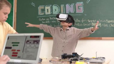 Kız kodlama sistemiyle uğraşırken metaworld 'e elektronik panoyla girmek için VR kulaklık takan bir çocuk. Çeşitli öğrencilerden oluşan bir grup program geliştirmek ve mühendislik kodu yazmak için birlikte çalışıyor. Pedagoji.